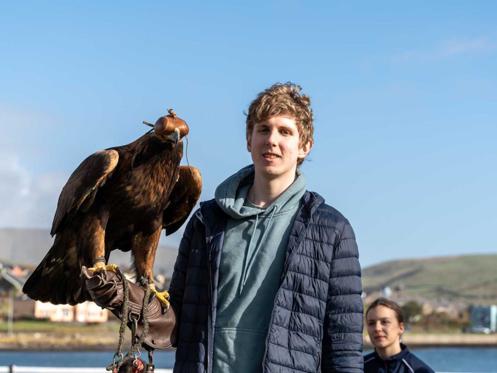 A young man with a bird perched on his arm