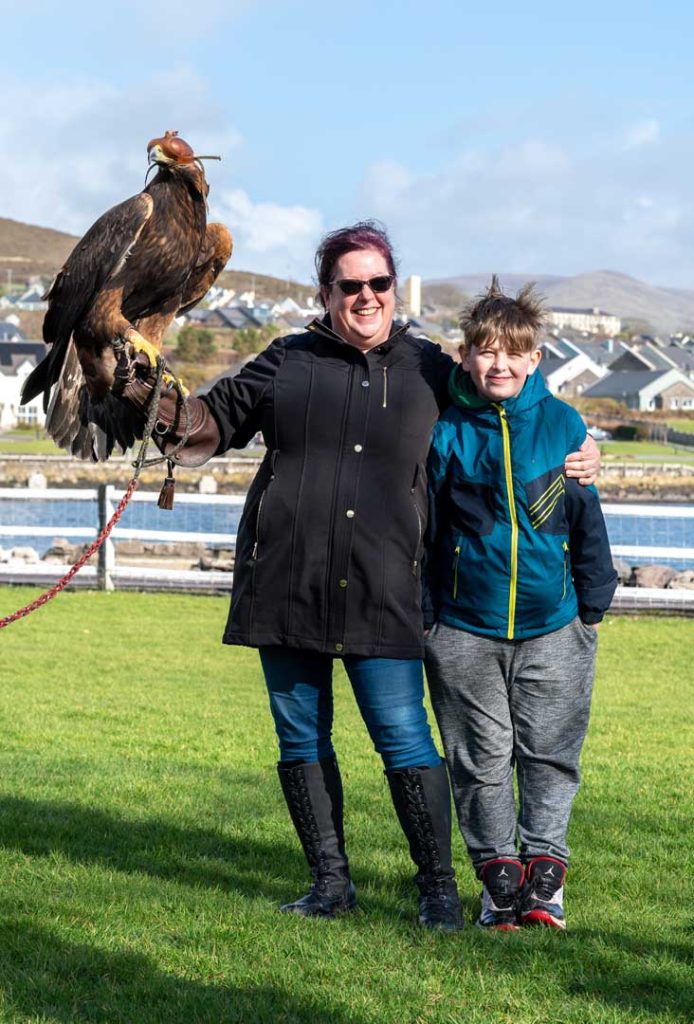 A mother and son holding a bird with blinders on