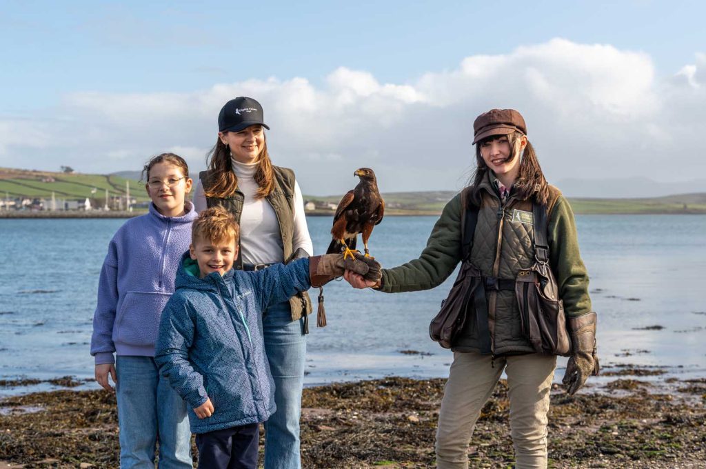 A family posing with a bird near the water