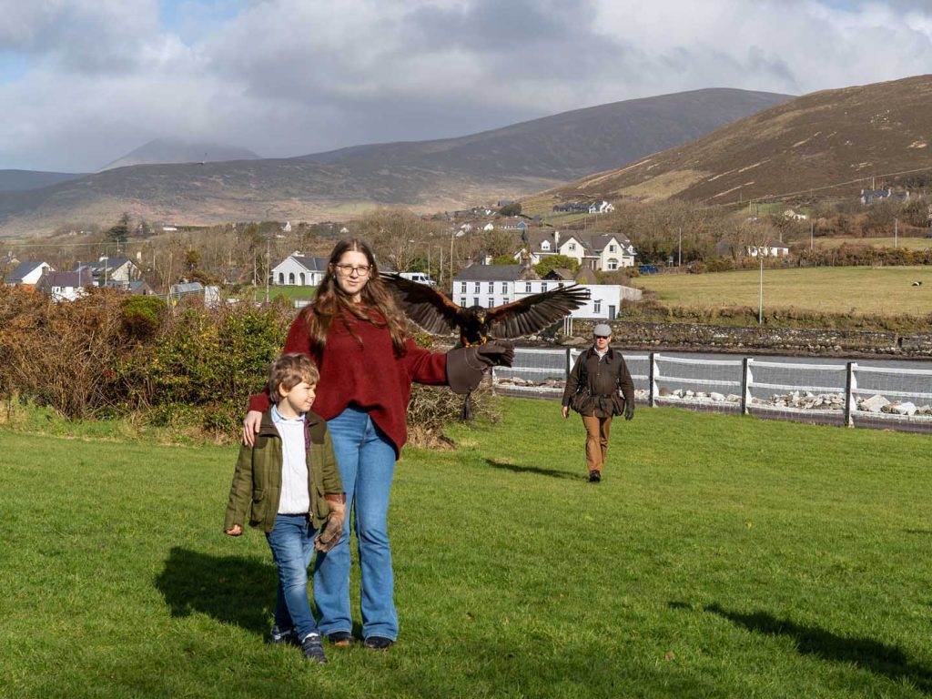 A bird landing on a sisters arm while her brother looks on