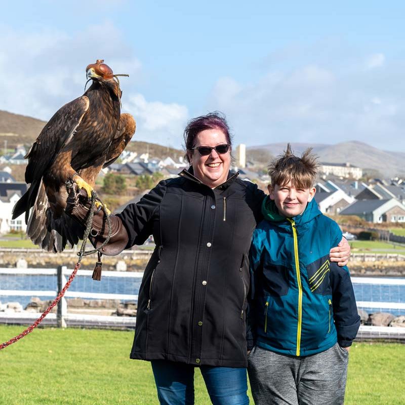 A mother and son posing with a large hawk